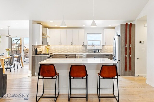 kitchen with a kitchen island, a kitchen breakfast bar, tasteful backsplash, a sink, and appliances with stainless steel finishes
