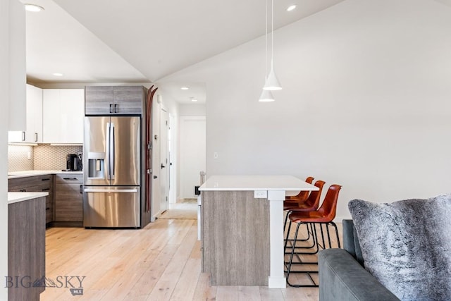 kitchen with stainless steel fridge, light countertops, light wood-style floors, and a breakfast bar