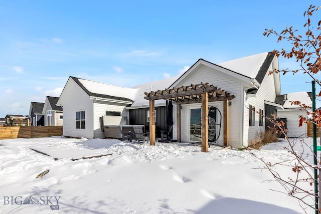 snow covered back of property featuring fence and a pergola