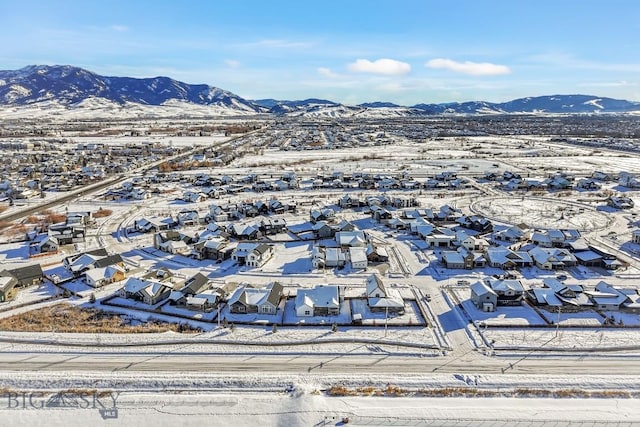 snowy aerial view with a mountain view and a residential view