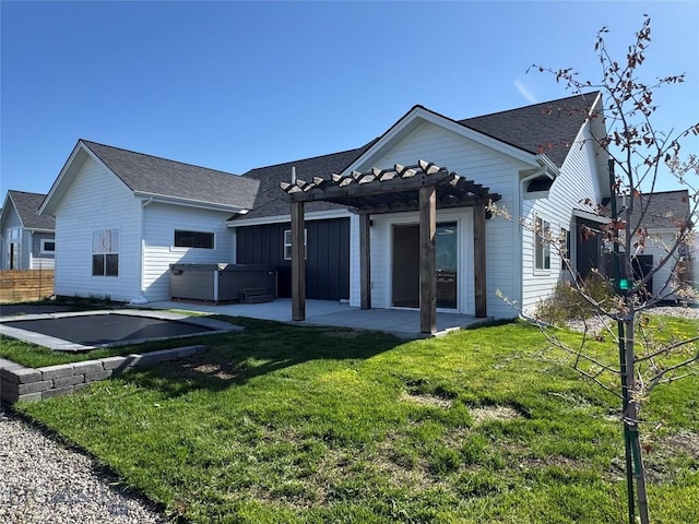 rear view of property featuring roof with shingles, a pergola, a hot tub, a patio area, and a yard