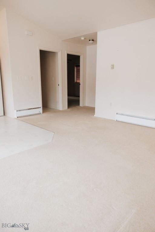 unfurnished room with light carpet and a baseboard heating unit