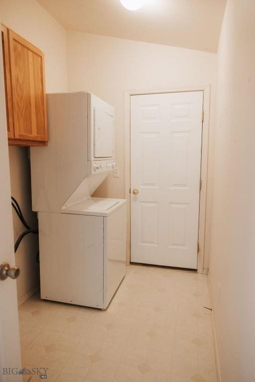 laundry room featuring cabinets and stacked washing maching and dryer