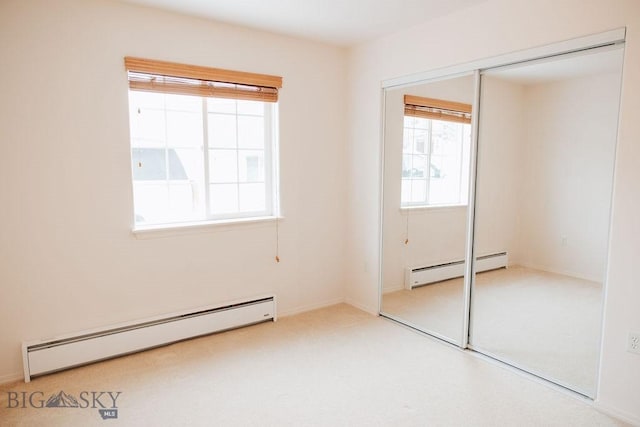 unfurnished bedroom featuring a baseboard radiator, light carpet, and a closet