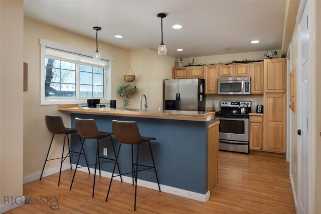 20 Talon Way Unit D, Bozeman, MT 59718 - kitchen featuring stainless steel appliances, a kitchen breakfast bar, a peninsula, light wood-style flooring, and hanging light fixtures