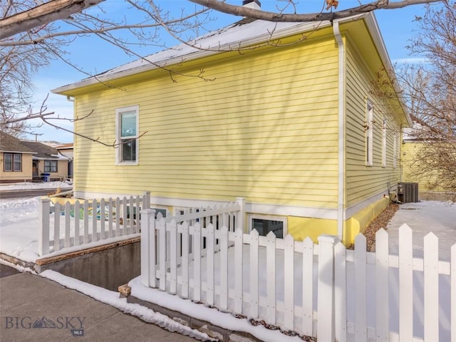 snow covered property with central air condition unit