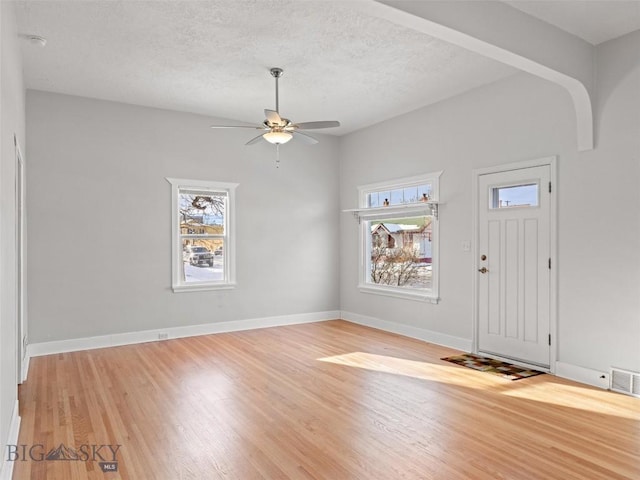 foyer entrance with ceiling fan, light hardwood / wood-style flooring, and a textured ceiling