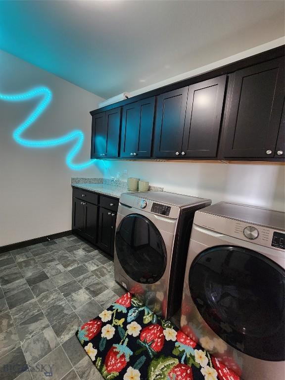 clothes washing area featuring baseboards, cabinet space, and washing machine and dryer