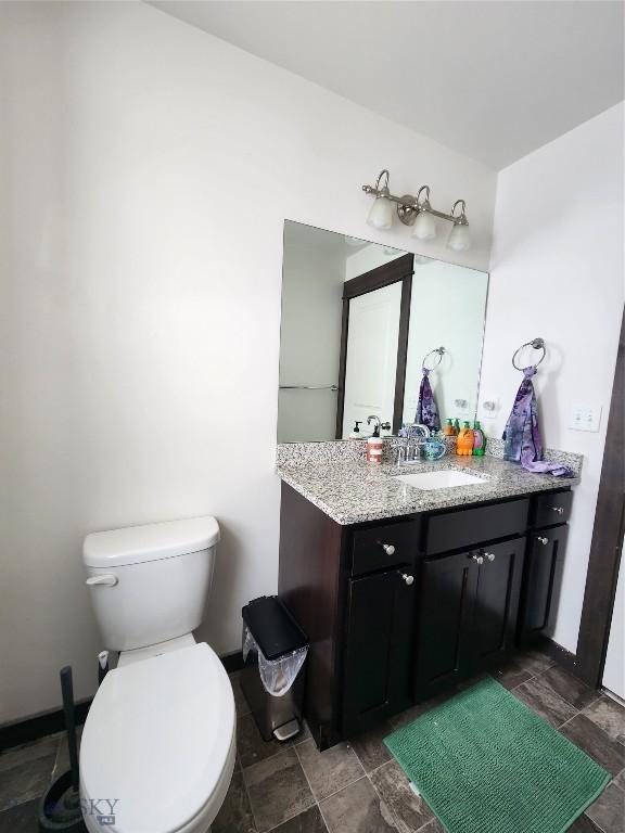 bathroom with toilet, vanity, and stone finish floor