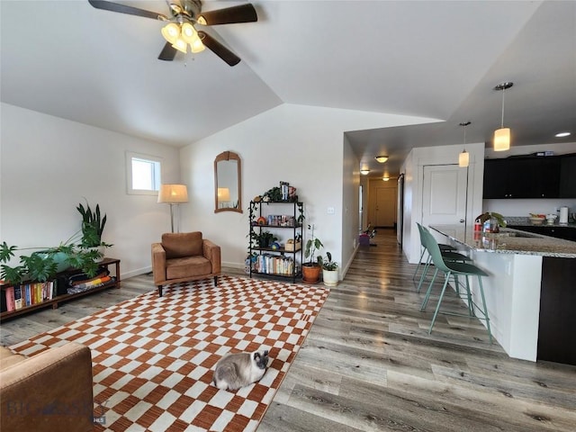 living room with lofted ceiling, wood finished floors, baseboards, and ceiling fan