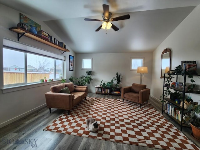 living area featuring ceiling fan, wood finished floors, baseboards, and vaulted ceiling