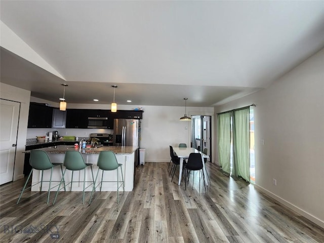 kitchen with light wood-type flooring, appliances with stainless steel finishes, and a kitchen island with sink