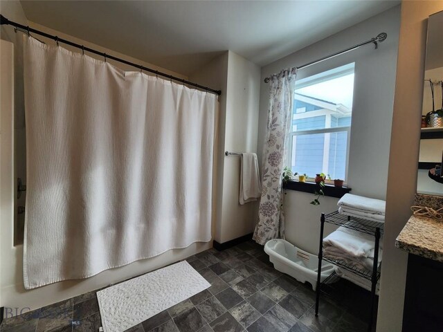 full bath featuring stone finish flooring and vanity