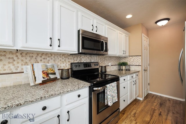 kitchen featuring dark hardwood / wood-style floors, white cabinetry, decorative backsplash, stainless steel appliances, and light stone countertops