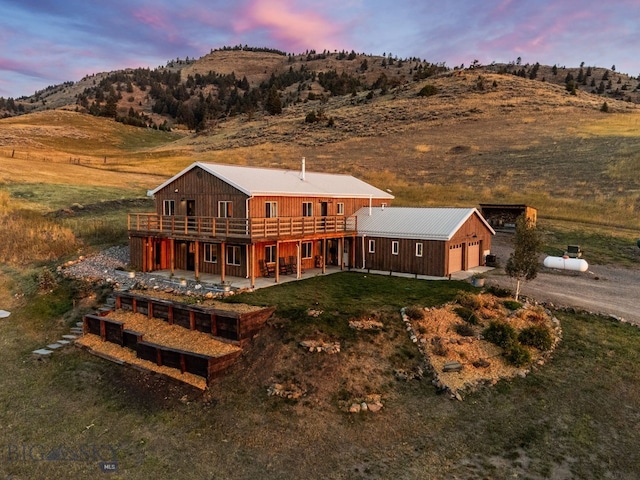 back house at dusk with a deck with mountain view