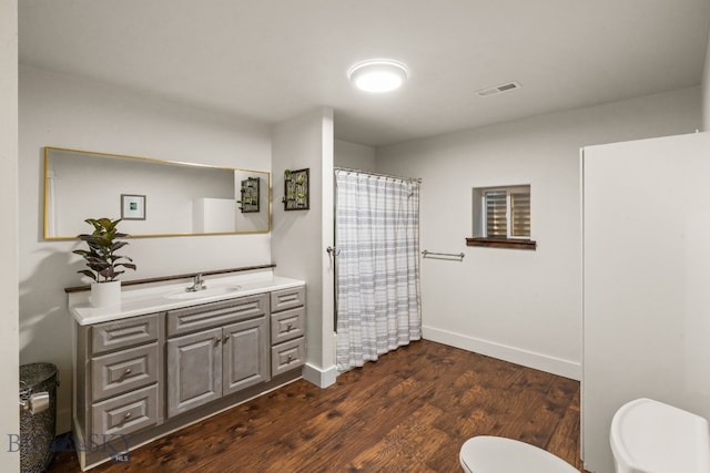 bathroom featuring hardwood / wood-style flooring, vanity, a shower with shower curtain, and toilet