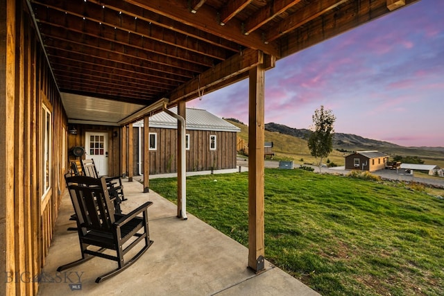 patio terrace at dusk featuring a yard and a mountain view