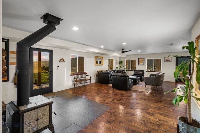 living room featuring ceiling fan, a wood stove, and dark hardwood / wood-style floors