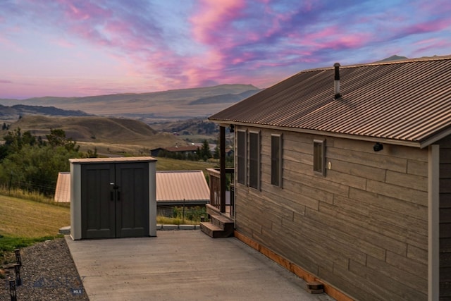 patio terrace at dusk with a deck with mountain view and a storage unit