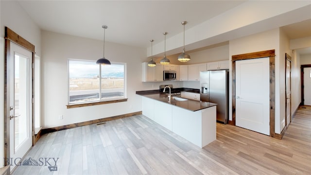 kitchen with sink, appliances with stainless steel finishes, hanging light fixtures, white cabinets, and kitchen peninsula