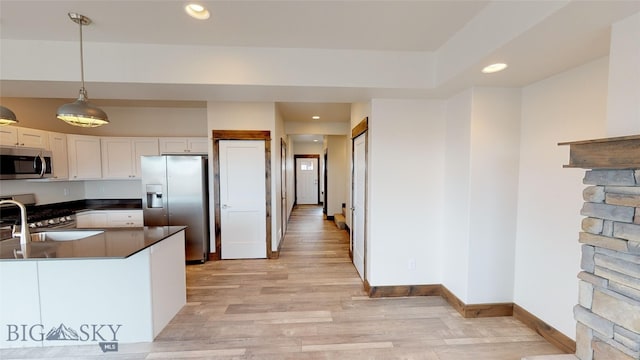 kitchen featuring sink, white cabinetry, decorative light fixtures, light hardwood / wood-style flooring, and appliances with stainless steel finishes