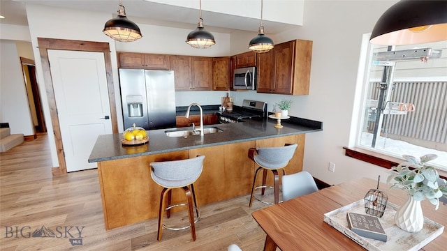 kitchen featuring a breakfast bar, sink, decorative light fixtures, appliances with stainless steel finishes, and kitchen peninsula