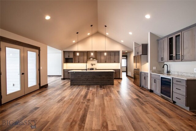 kitchen with pendant lighting, an island with sink, high end refrigerator, wine cooler, and dark hardwood / wood-style flooring