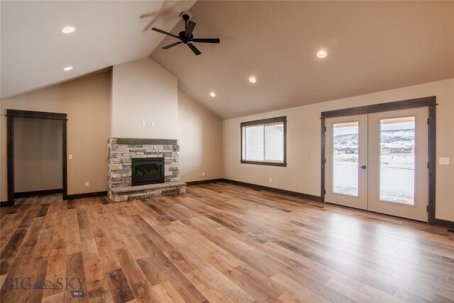 unfurnished living room featuring french doors, light wood-style floors, a stone fireplace, baseboards, and ceiling fan