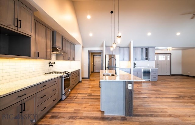 kitchen featuring wall chimney range hood, beverage cooler, appliances with stainless steel finishes, and a sink