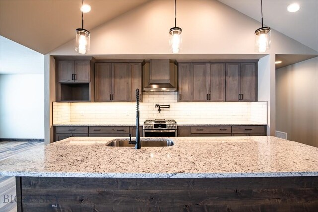 kitchen with premium range hood, stainless steel range, light stone counters, and hanging light fixtures