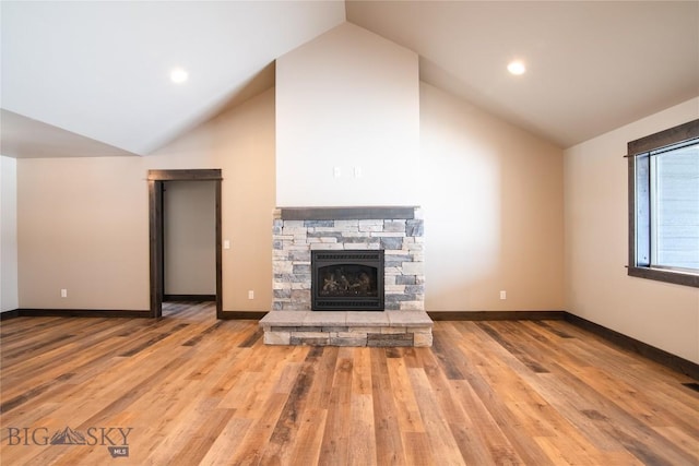 unfurnished living room featuring baseboards, high vaulted ceiling, wood finished floors, and a fireplace