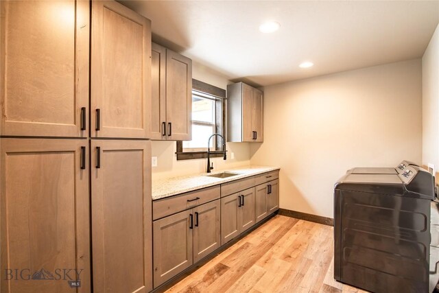 kitchen featuring sink, washer and dryer, and light wood-type flooring