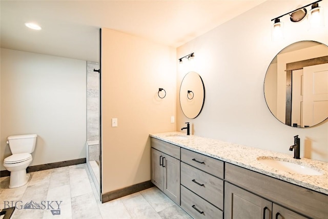 bathroom featuring double vanity, toilet, baseboards, and a sink