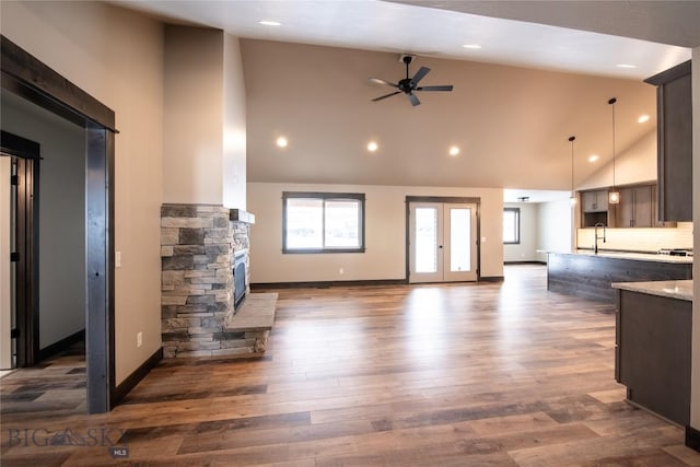 kitchen with ceiling fan, dark wood finished floors, open floor plan, a stone fireplace, and a sink