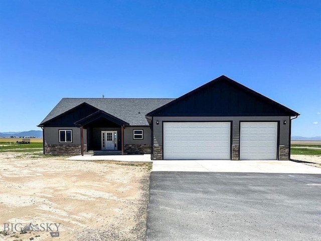 view of front of home featuring a garage, stone siding, and driveway