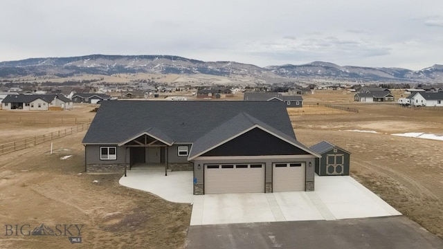 view of front of house featuring concrete driveway, an attached garage, fence, and a mountain view