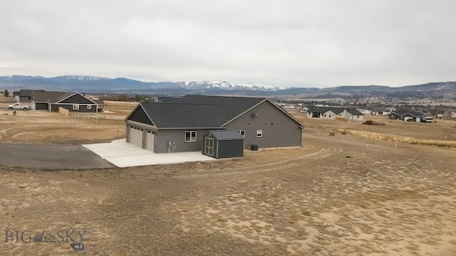 rear view of property featuring a mountain view, an outbuilding, and a storage shed