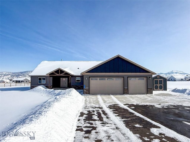 view of front of property featuring board and batten siding, fence, stone siding, an attached garage, and a storage unit