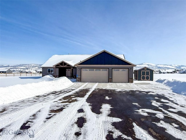 view of front facade with a storage unit, an outbuilding, driveway, stone siding, and fence