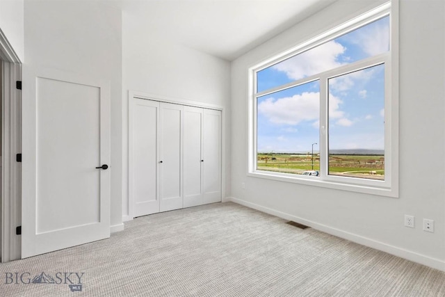 unfurnished bedroom with light colored carpet and a closet