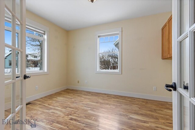 empty room with light hardwood / wood-style flooring, french doors, and plenty of natural light