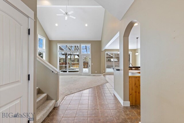 carpeted foyer entrance with high vaulted ceiling, a wealth of natural light, and ceiling fan