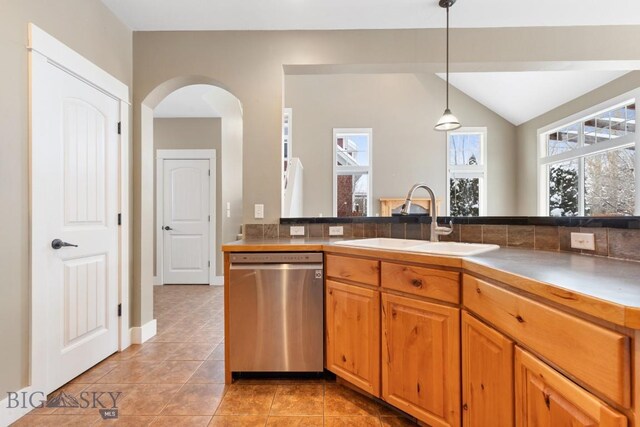 kitchen featuring light tile patterned flooring, lofted ceiling, sink, decorative light fixtures, and stainless steel dishwasher