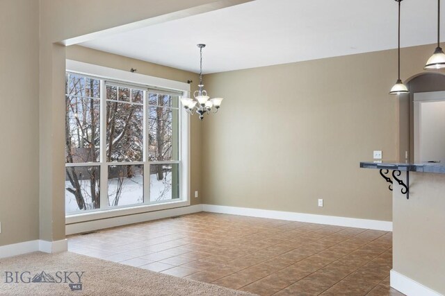 unfurnished dining area featuring an inviting chandelier, tile patterned floors, and plenty of natural light