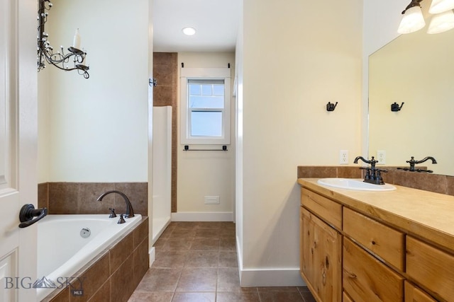 bathroom featuring tile patterned flooring, vanity, and tiled tub