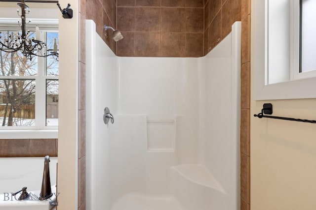 bathroom featuring an inviting chandelier and a tile shower