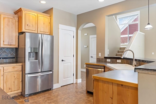 kitchen with tasteful backsplash, decorative light fixtures, light brown cabinets, and appliances with stainless steel finishes