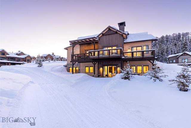 snow covered rear of property with a deck