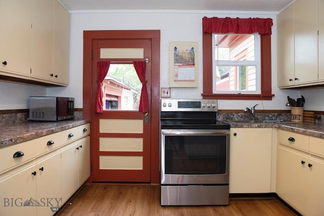 kitchen featuring cream cabinets, light hardwood / wood-style floors, and electric stove