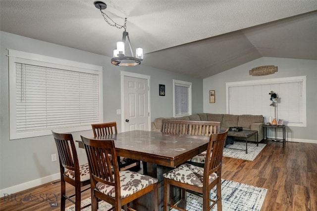 dining area with lofted ceiling, dark hardwood / wood-style floors, a textured ceiling, and a chandelier